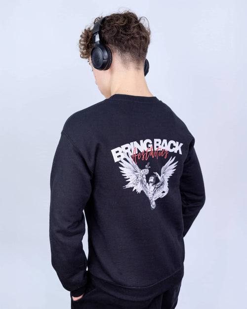 Person wearing a black sweatshirt with a design and text on the back, standing against a light gray background.