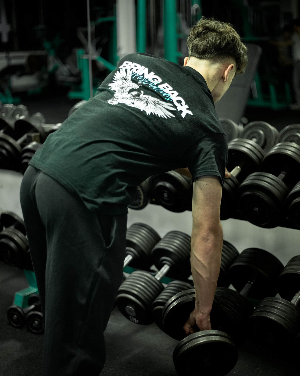 Person in a gym setting with weights and 'BRING BACK AESTHETICS' t-shirt.