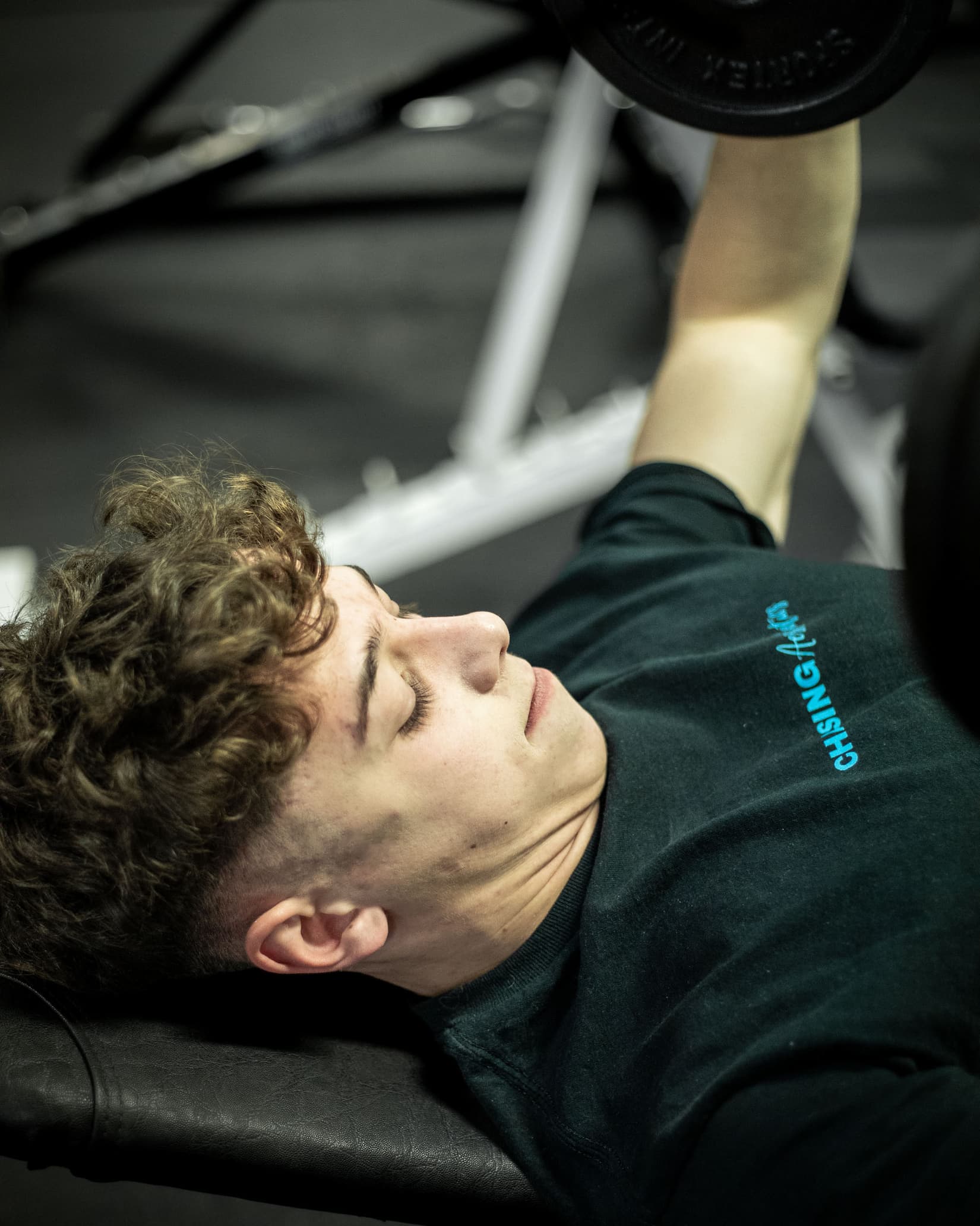 Person lifting weights on a bench press in a gym setting