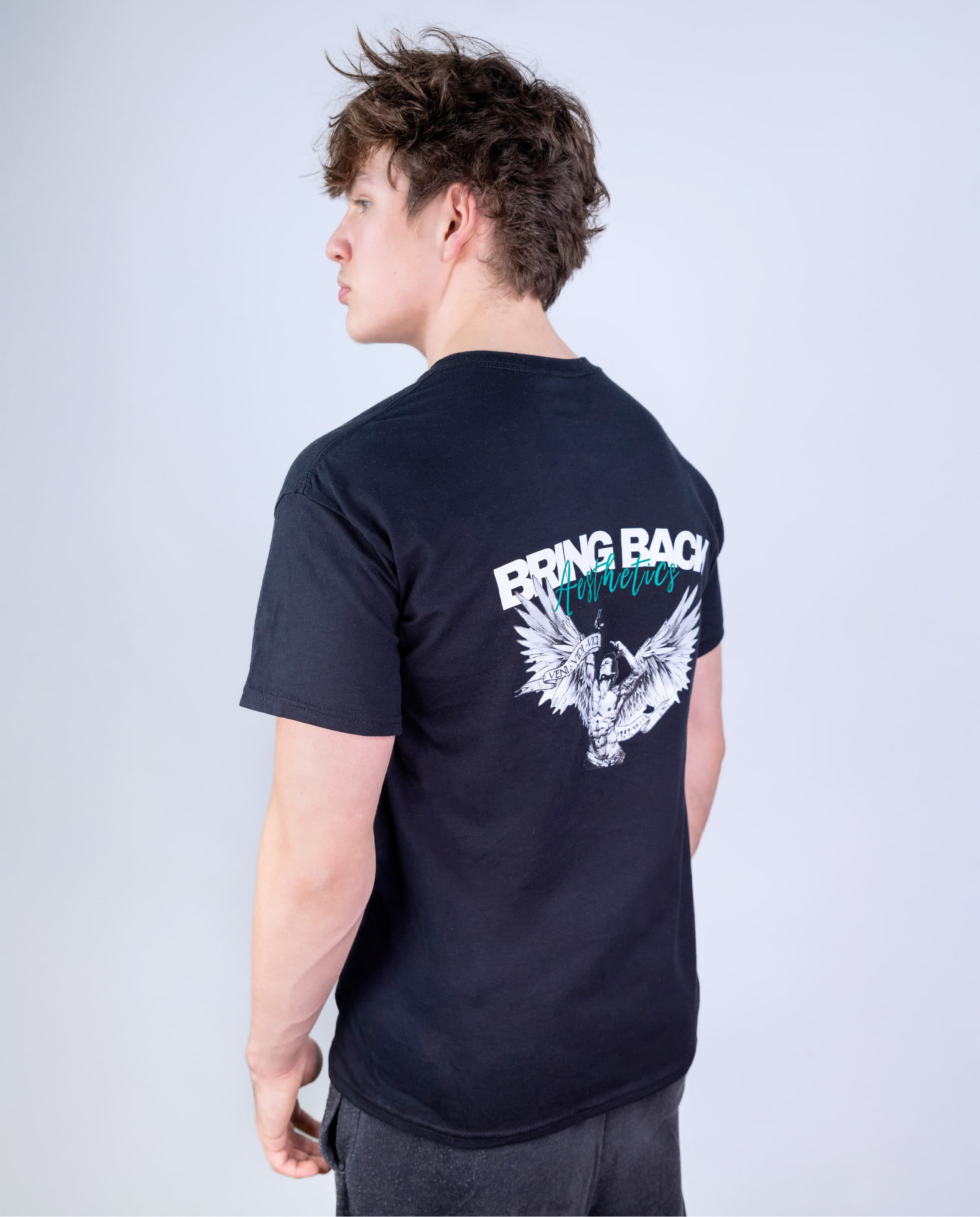 Person wearing a black t-shirt with a graphic design on the back against a light gray background