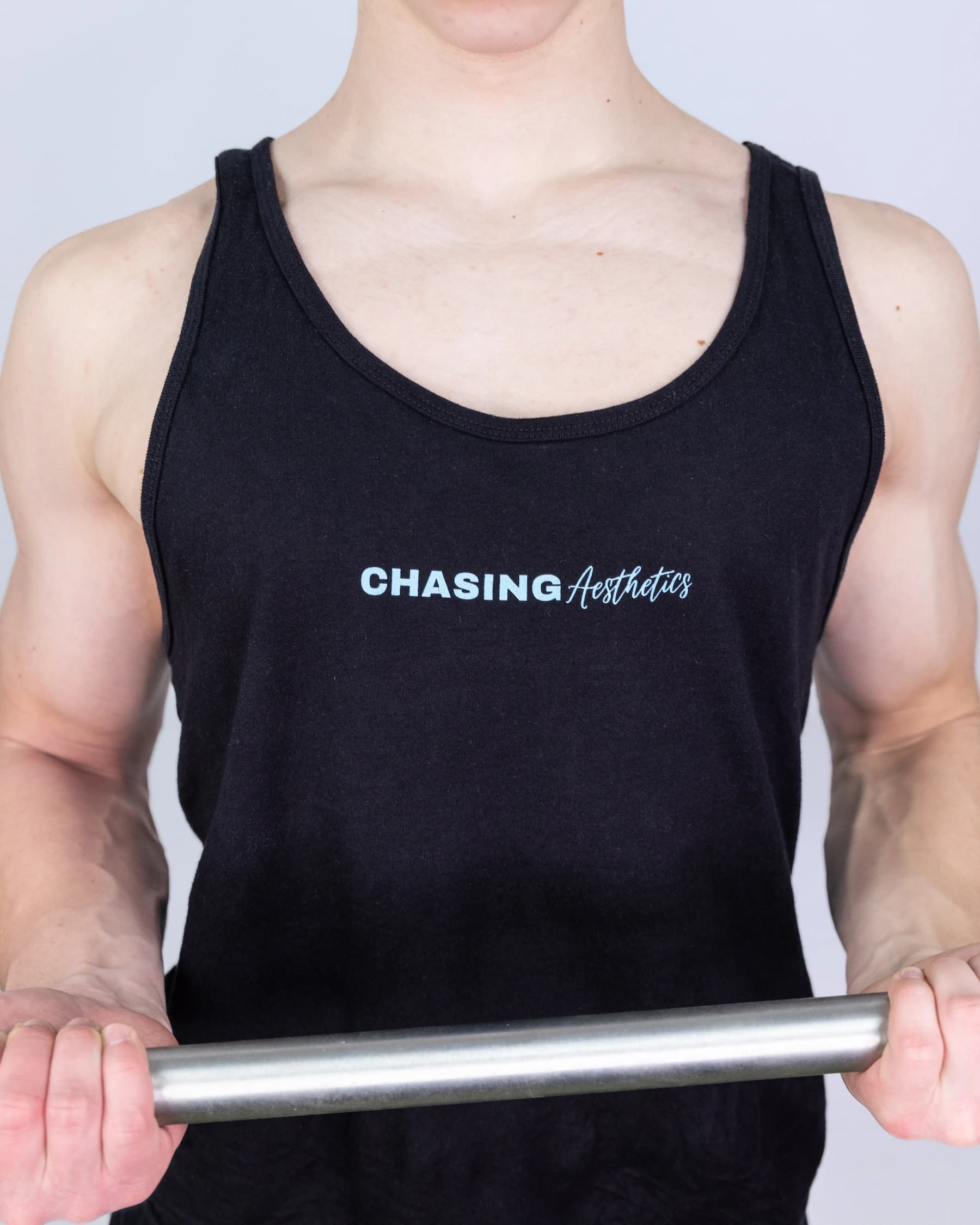 Person wearing a black tank top with 'Chasing Aesthetics' text, holding a barbell.