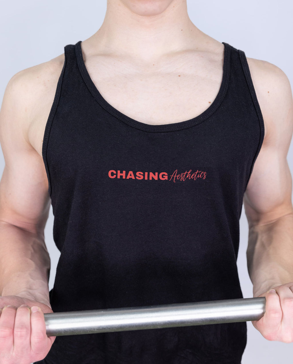Person wearing a black tank top with 'Chasing Aesthetics' text, holding a barbell.