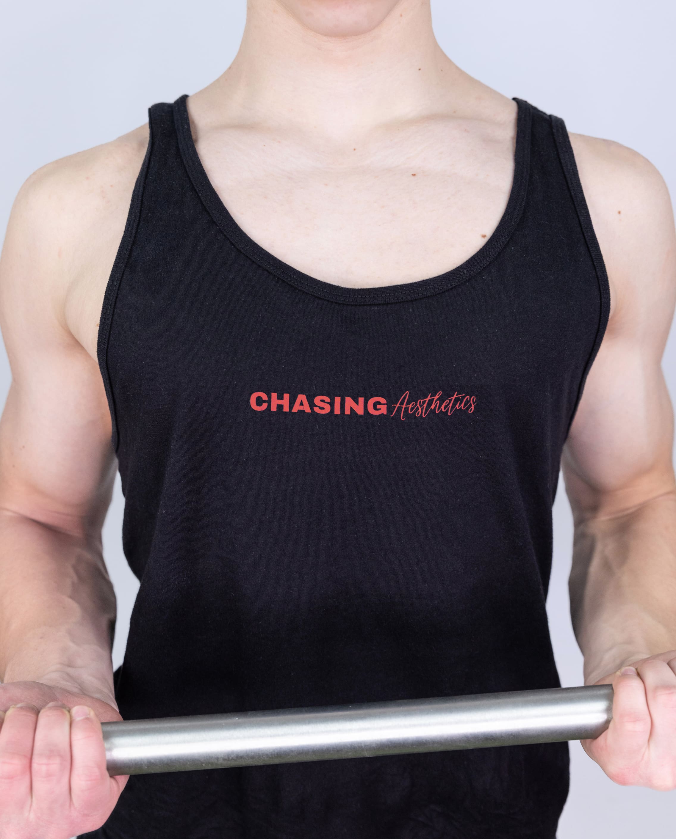 Person wearing a black tank top with 'Chasing Aesthetics' text, holding a barbell.